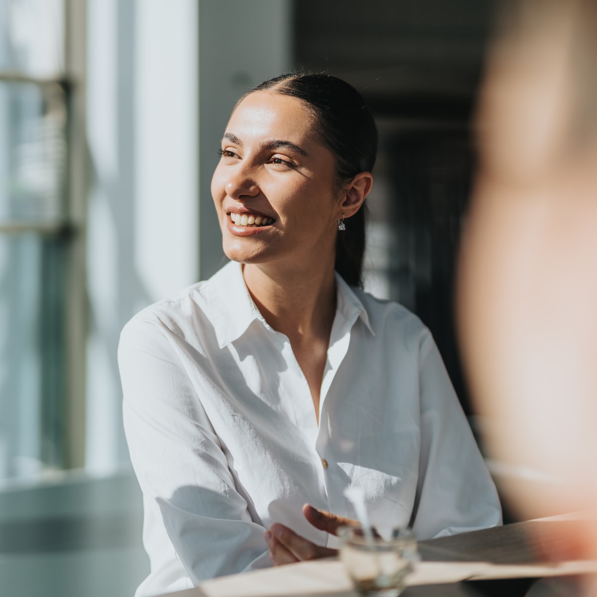 A woman in a white button up is looking left.