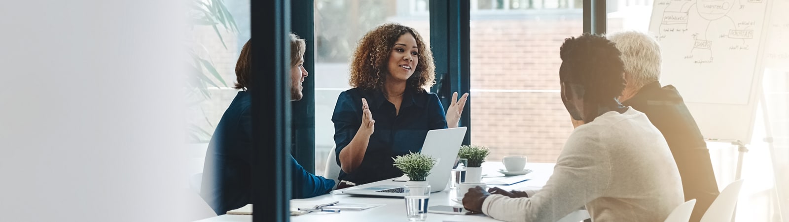A group of four business looking people are sitting around a table having a discussion.